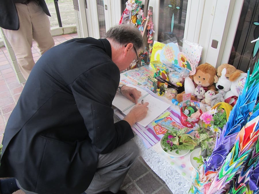 In the Japanese town of Shinchi-cho, Archbishop Fred Hiltz writes his condolences for a teacher and 11 kindergarten students who died in the March 2011 earthquake and tsunami. Photo: Paul Feheley.