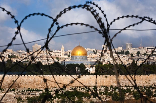 The Old City of Jerusalem, seen through razor wire, illustrating the Holy Land's history of division and conflict. Photo: Ryan Rodrick Beiler