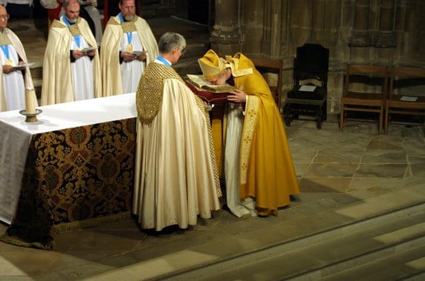 The Dean of Canterbury holds the Canterbury Gospels, as Archbishop Rowan Williams kisses the ancient book in reverence to its message. Photo: archbishopofcanterbury.org