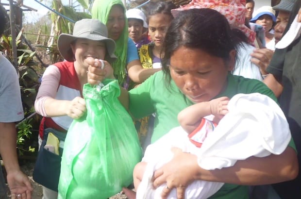 A woman receives food aid from PWRDF-partner the Relief Mission in Guinwa, Bantayan Island. Photo: PWRDF