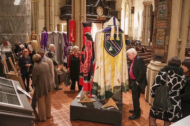 Visitors at the Oct. 24 opening of the Sacred Stitches exhibit, including Archbishop Michael Peers, former primate of the Anglican Church of Canada, survey the intricate needlework in the Christian, Muslim, Jewish, and Buddhist articles on display. Photo: Michael Hudson