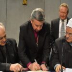 Bishop Sanchez Sorondo (left), Dr. Mahmoud Azab (right) and Andrew Forrest (behind) look on as Archbishop David Moxon affixes his signature to the historic agreement to combat modern slavery and human trafficking.