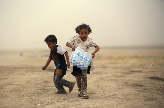 A young girl who fled the violence in Mosul carries bottled water for her family at a camp on the outskirts of Arbil, capital of Iraq’s Kurdistan region, where thousands of Christians have taken refuge. Photo: Reuters