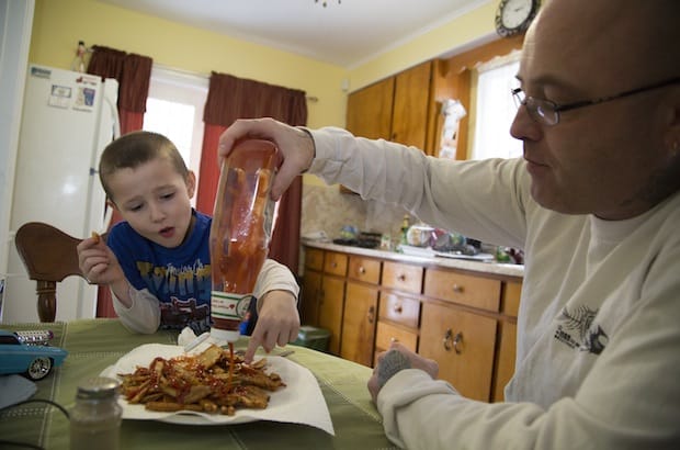 John Gnatiuk shares a plate of fries with his son, Landon, in Sydney River, N.S. Gnatiuk was laid off last December from his job as a heavy equipment operator and truck driver in Fort McMurray, Alta. The downturn in oil prices has affected workers like him, who commute for work in the oil sands. Photo: Steve Wadden/Reuters