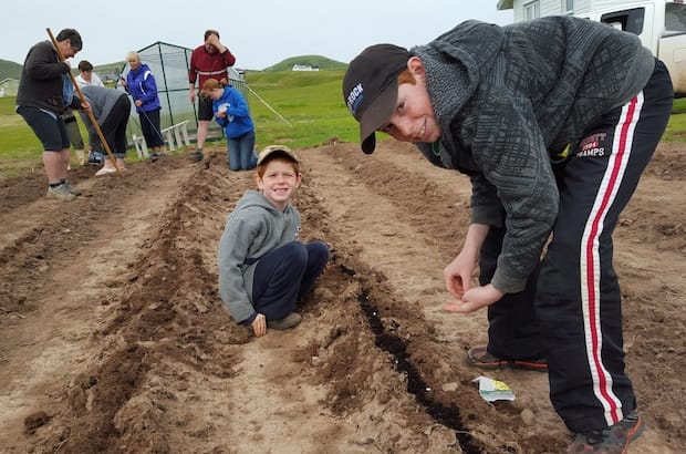 Ethan Aitkens, watched by Carter Patton, plants a seed while(L-R) Thelma Feltmate, Pauline Boudreau (bending) Robin Aitkens, DarleneChenell, Jonathan Patton and Alexis Burris prepare the furrows. Photo: JeffreyMetcalfe