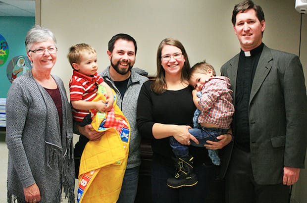 Colin clutches a bright yellow quilt, handmade for him by a Riverview parishioner. With him are (L to R) the Rev. Barbara Haire, his parents Paul and Kimberly, his brother Isaac and Archdeacon Brent Ham. Photos: Contributed