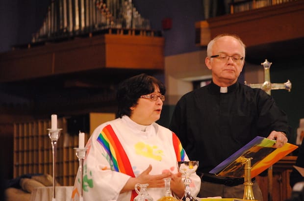 The Rev. Samantha Caravan, assisted by Canon Douglas Graydon, presides at a “queer Eucharist” in the church of St. John’s West Toronto. Photo: Tali Folkins