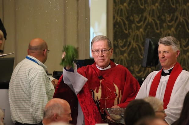 Archbishop Fred Hiltz sprinkles the gathering with holy water in a rite of blessing known as asperges, at the opening Eucharist of the 41st General Synod. Photo: Art Babych