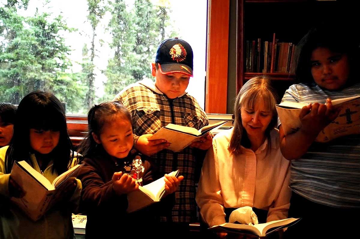 Naskapi child read the Naskapi New Testament Bible aloud with Lana Martens, who began the first translation work in the 1970s.