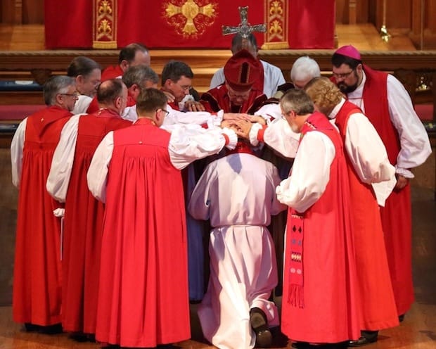Archbishop Fred Hiltz prays as the bishops lay their hands on the bishop-elect. Photo: Art Babych