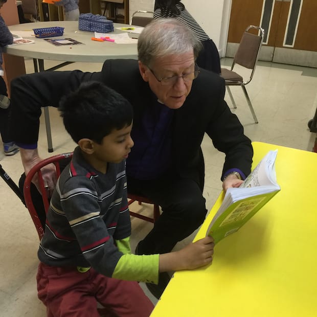Primate Fred Hiltz reads to a child at an after-school program funded by the Anglican Foundation of Canada in St. Jamestown, Toronto. Photo: Contributed
