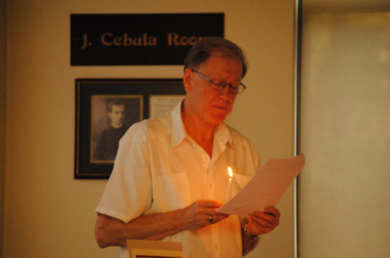 Archbishop Fred Hiltz, primate of the Anglican Church of Canada, lights a candle between prayers for people involved in human trafficking at a session of the Council of General Synod (CoGS) Saturday, June 24. Photo: Tali Folkins